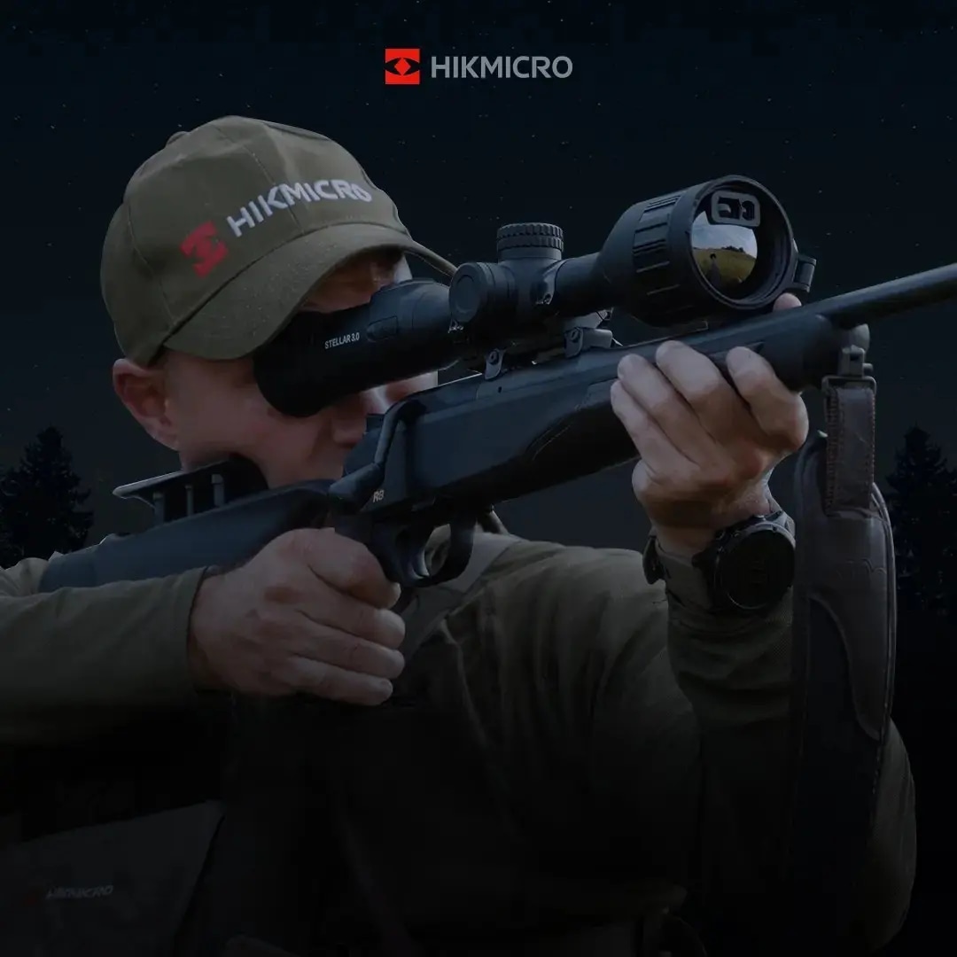 Hunter using Hikmicro thermal optics mounted on rifle in low-light conditions, demonstrating precision targeting with advanced thermal imaging technology.