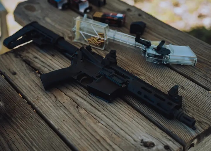 Tippmann Arms tactical rifle displayed on rustic wooden surface with ammunition and speed loader, showcasing premium build quality and versatile tactical features for shooting enthusiasts and hunters